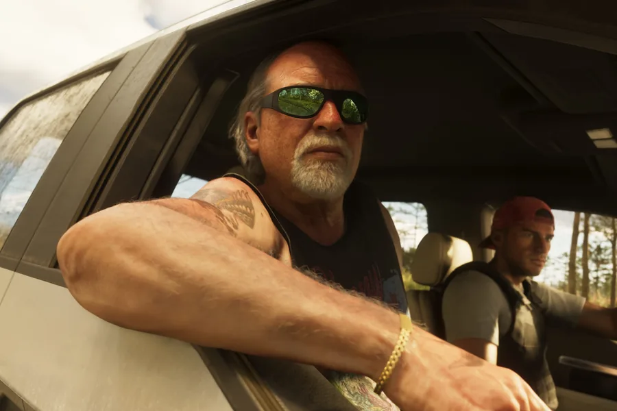Brian Heder, an older man with a grey beard and mirrored sunglasses, his tattooed arm resting on the open window of a pickup, Jason at the wheel beside him.
